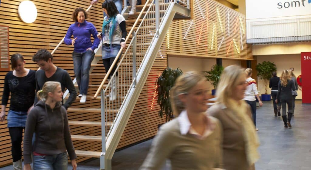 Mensen lopen en dalen een trap af in onderwijsgebouw voor fysiotherapie.