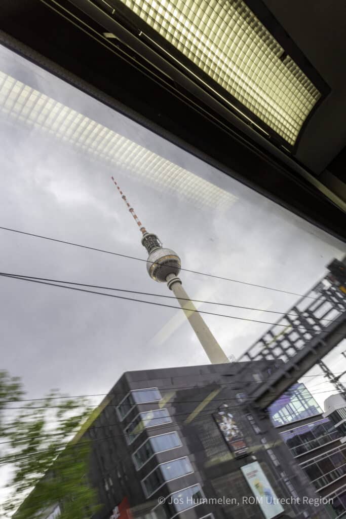 De televisietoren van Berlijn gezien door een treinraam op een bewolkte dag.